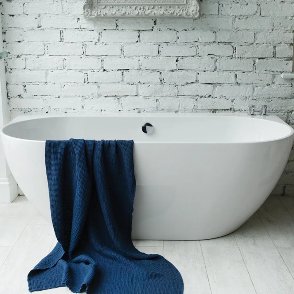 waters loche 1660mm back to wall freestanding bath front angle image with blue towel hanging off in front of white brick wall